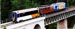 试验列车由两台BLS 机车组成，牵引带变轨距转向架的MOB全景客车穿越Bunschbach高架桥运行